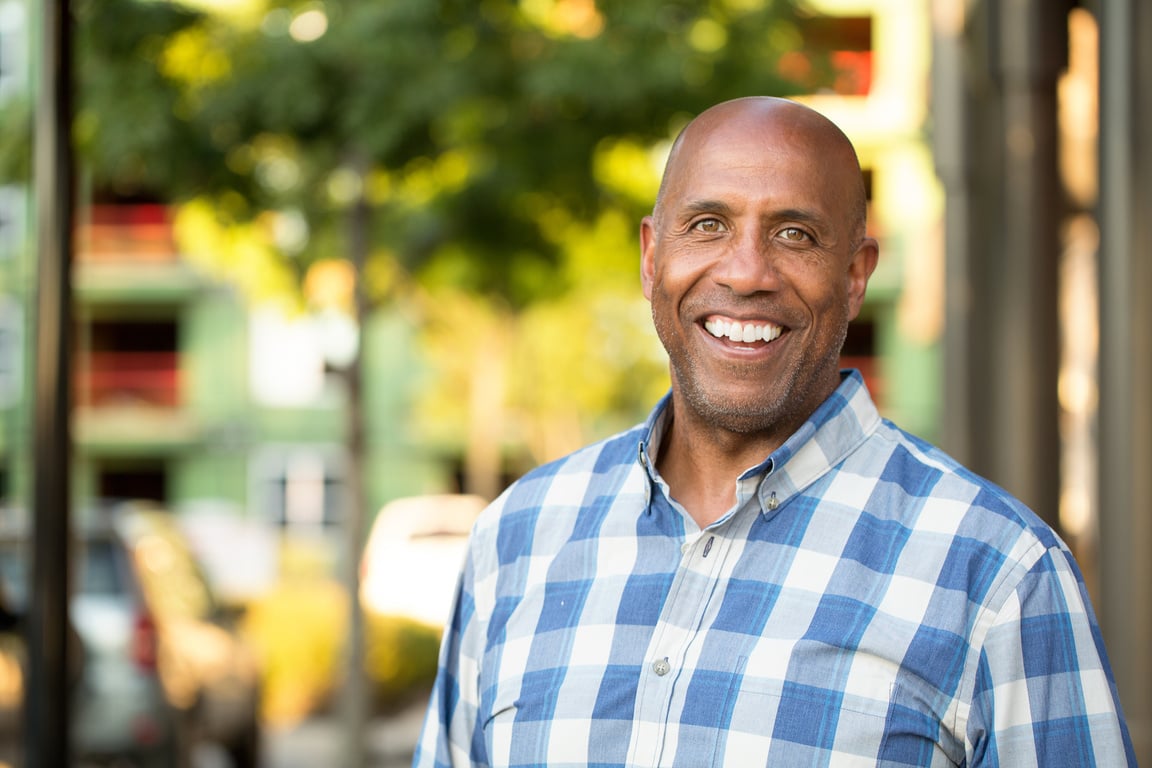 Happy mature African American man smiling outside.